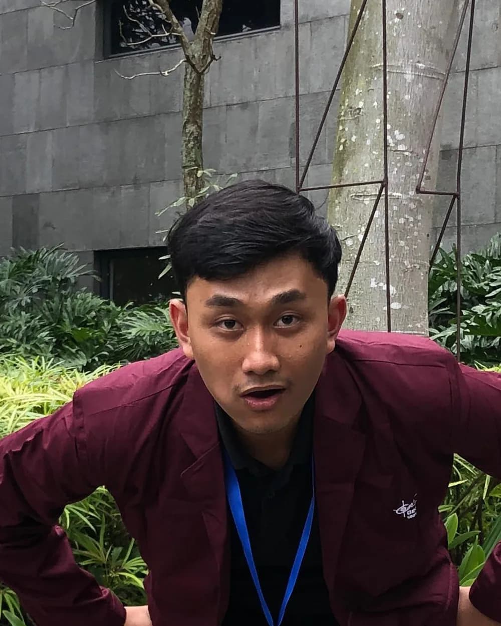 Panji Putra Ardian in a maroon blazer, leaning forward with his hands on his hips